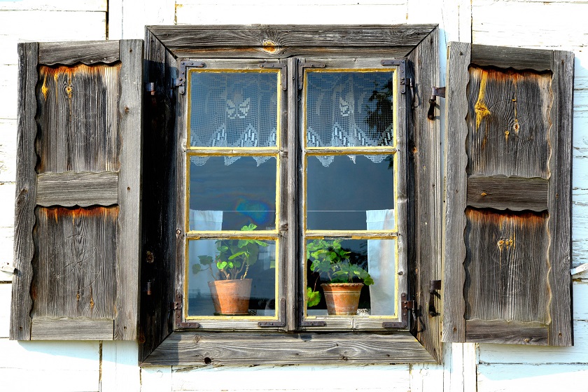 stare drewniane okno z okiennicami i kwiatami